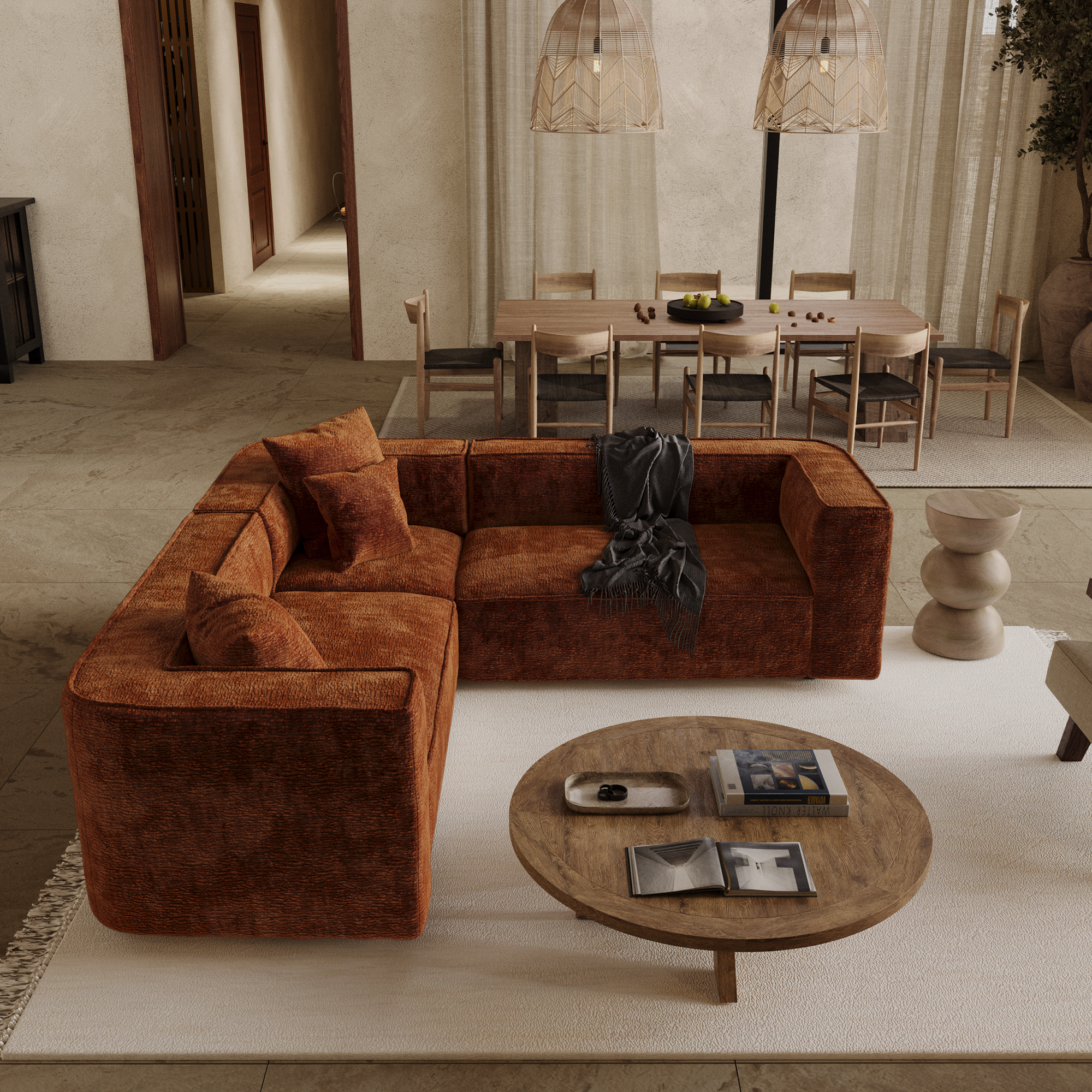 Salon chaleureux avec canapé d'angle symétrique en velours noisette, table basse en bois ronde et tapis écru