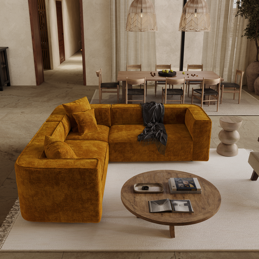 Canapé d'angle symétrique en velours jaune moutarde, avec une table basse ronde en bois et un grand tapis clair, dans un salon spacieux